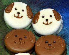 four decorated cookies in the shape of dogs on a green cloth with blue and white background