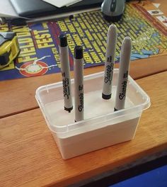 three pens sitting in a container on top of a desk