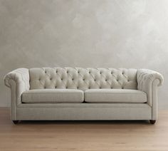 a white couch sitting on top of a hard wood floor next to a gray wall