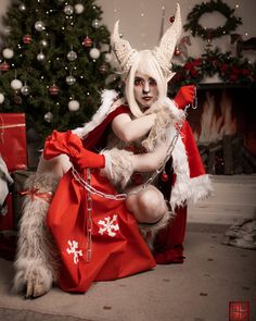 a woman dressed as santa clause sitting next to a christmas tree