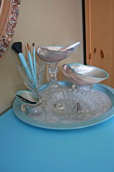 there is a blue table with glass dishes and spoons on it in front of a mirror