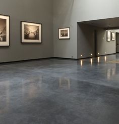 an empty room with pictures hanging on the wall and lights in the floor below it