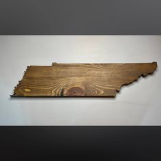 a wooden state shaped wall hanging on a white wall with wood grain inlays