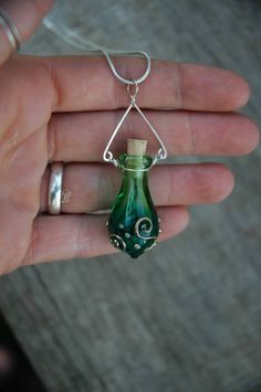 a hand holding a green glass bottle with a corkscrew hanging from it's side