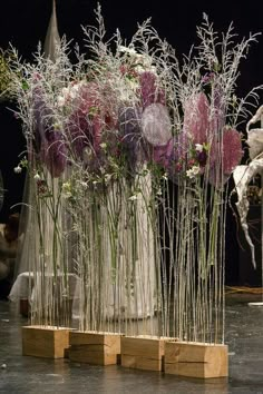 several vases filled with purple flowers on top of a wooden block in front of a black background