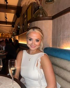 a woman sitting at a table with a glass of wine