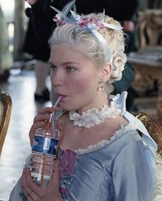 a woman in a blue dress holding a water bottle and drinking from a plastic cup