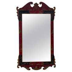 a red mirror sitting on top of a white wall next to a wooden frame with an ornate design