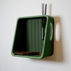 a green object with sticks sticking out of it's side hanging on a wall