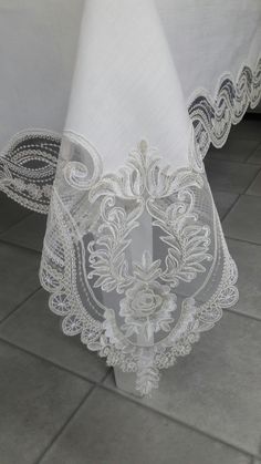 white table cloth with intricate design on the top and bottom, sitting on a tile floor