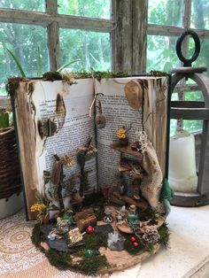 an open book sitting on top of a table filled with lots of books and plants