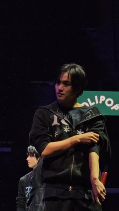 two men standing next to each other in front of a sign