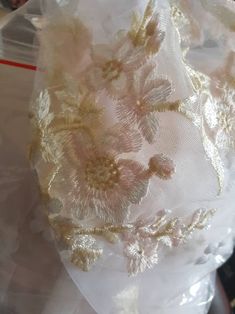 a white dress with gold embroidered flowers on it's chest and back, sitting on a plastic bag