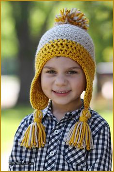 a young boy wearing a knitted hat with tassels and smiling at the camera