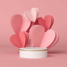 pink paper hearts in a white container on a pink background