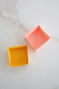 two orange origami boxes sitting on top of a white counter next to each other