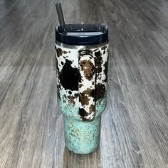 a cup with a straw in it sitting on a wooden table next to a floor