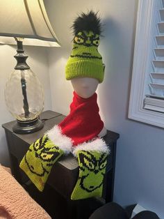 a knitted hat and scarf on top of a night stand with a lamp next to it