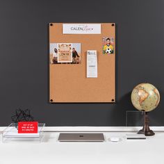 a cork board with magnets and pictures on it in front of a gray wall