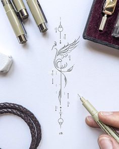 a person is drawing on paper with some pens and other items around it, including fountain pens