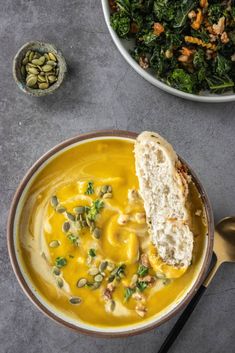 a bowl filled with soup next to a spoon and some other food on the table