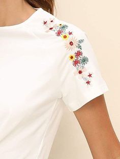 a woman wearing a white t - shirt with colorful flowers on the sleeves and shoulder