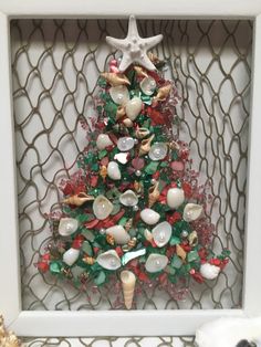 a christmas tree made out of seashells in a white frame on a shelf