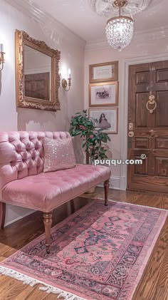 a pink couch sitting on top of a wooden floor next to a rug and mirror