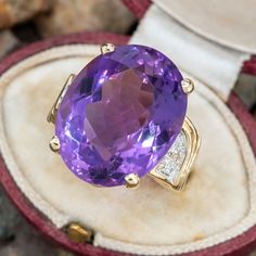 This amethyst cocktail ring is centered with one (1) oval mixed cut natural amethyst set into a four-prong setting. The shoulders of the ring are each accented with five (5), bead set, round brilliant cut diamonds. The ring measures 20.0mm at the top, rises 12.1mm above the finger, tapering to 3.3mm wide and 0.9mm thick at the base of the shank. The ring is currently a size 5. Formal Lavender Amethyst Ring With Oval Shape, Formal Lavender Oval Amethyst Ring, Formal Lavender Oval Ring, Oval Amethyst Ring With Gemstone Accents For Formal Occasions, Oval Amethyst Gemstones For Formal Occasions, Formal Oval Amethyst Gemstones, Oval Amethyst Ring With Gemstone Accents, Oval Purple Amethyst Ring With Gemstone Accents, Lavender Oval Amethyst Ring With Gemstone Accents