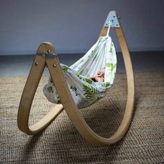 a baby laying in a hammock on top of a wooden stand with a green and white blanket