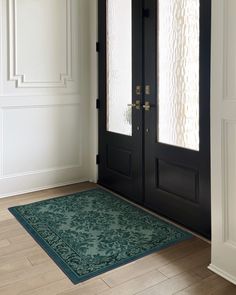 a black door with two glass panels and a green rug on the floor next to it