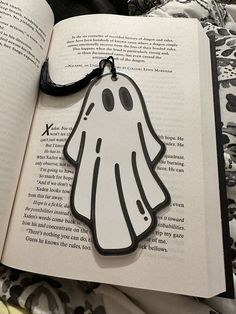 a bookmark with a ghost on it sitting in front of an open book,