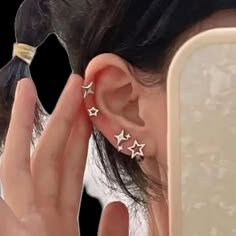 a woman is holding her ear up to the side with three stars on it's sides