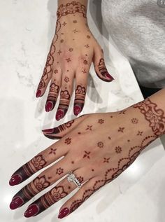 a woman's hand with henna tattoos on it and her hands painted red