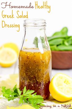 homemade healthy greek salad dressing in a glass jar with lemons and parsley on the side