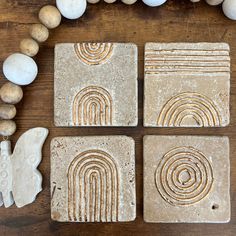 four stone coasters with designs on them sitting next to some rocks and eggs,