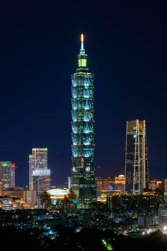 the city skyline is lit up at night with skyscrapers in the foreground and buildings on the other side