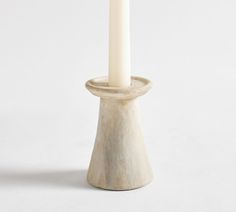 a white candle sitting on top of a wooden stand