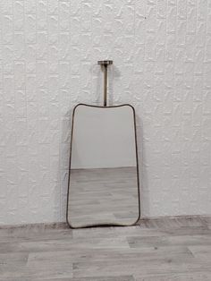 a mirror sitting on top of a wooden floor next to a wall with a hook