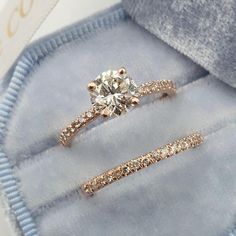 two diamond rings in a blue velvet box with the ring on it's side