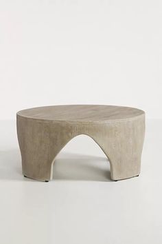 a white table with an arch shaped base on it's side, against a plain background