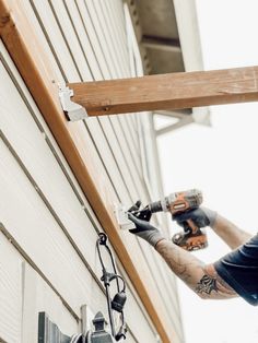 a man is doing some work on the side of a building while holding two drillers