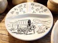 a white plate with drawings on it sitting on a wooden table next to other plates