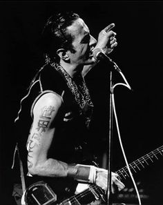 a black and white photo of a man singing into a microphone while holding a guitar