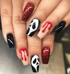 a woman's hand with red and black nail polish on it, decorated with skulls