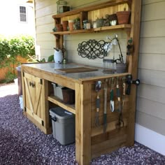 an outdoor potting station with gardening tools and pots on the outside wall, in front of a house