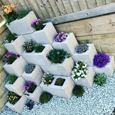 several cement planters are stacked on top of each other with flowers growing out of them