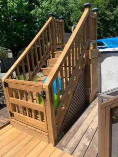 a wooden deck with an above ground swimming pool and stairs leading up to the upper level