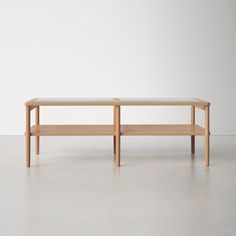 a wooden table sitting on top of a cement floor next to a white wall in an empty room