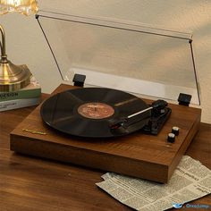 a record player sitting on top of a wooden table next to a lamp and papers